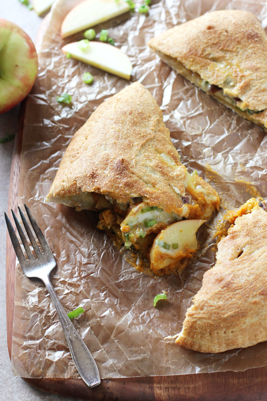 A sliced up Pumpkin, Apple and Cheddar Calzone on a cutting board.