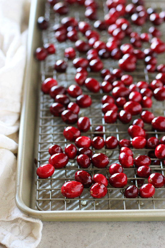 Fresh cranberries on a cooling rack set in a baking sheet.