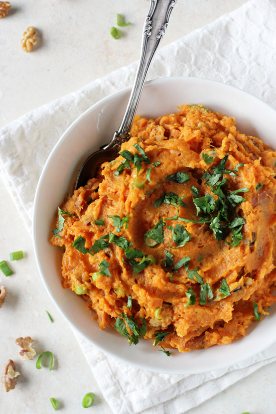 A white bowl filled with Savory Mashed Sweet Potatoes with a spoon in the dish.