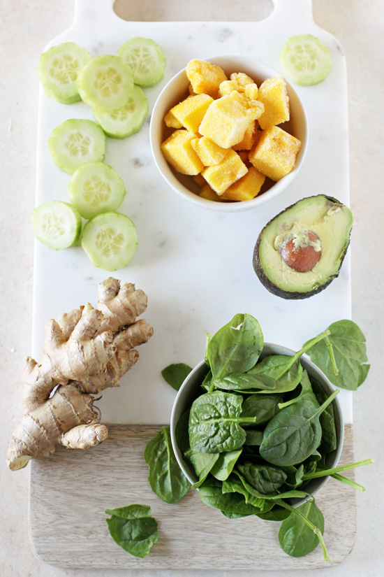 Diced mango, spinach, cucumber, ginger and avocado on a marble cutting board.
