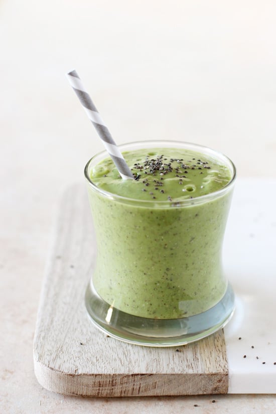 A glass filled with Avocado Green Smoothie and a grey straw.