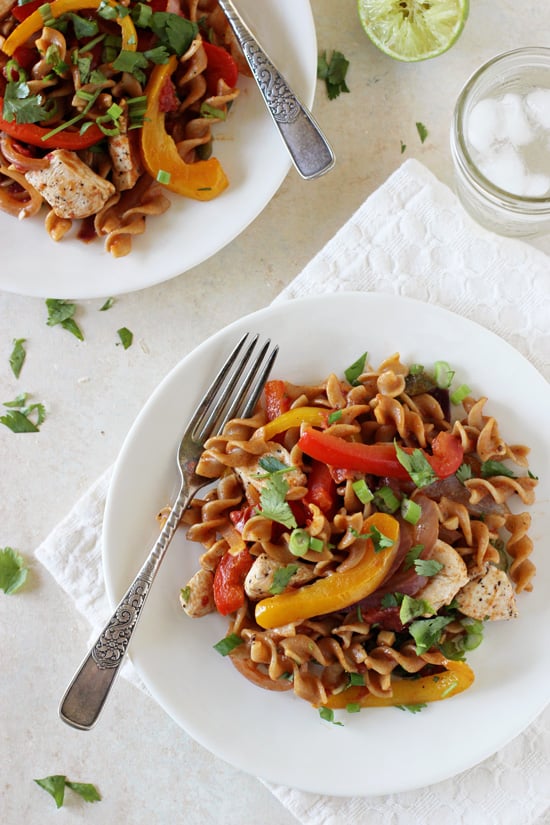 Two white plates filled with Skillet Chicken Fajita Whole Wheat Pasta.