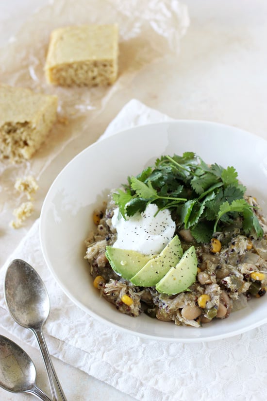 A white bowl filled with Slow Cooker Green Chicken Chili topped with avocado and cilantro.