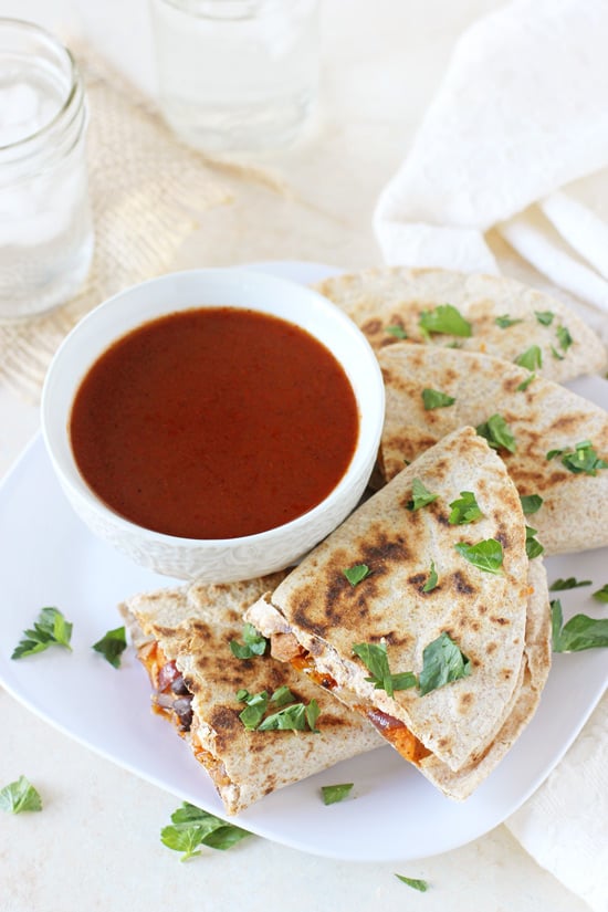 Roasted Vegetable Quesadillas on a white plate with a bowl of enchilada sauce.