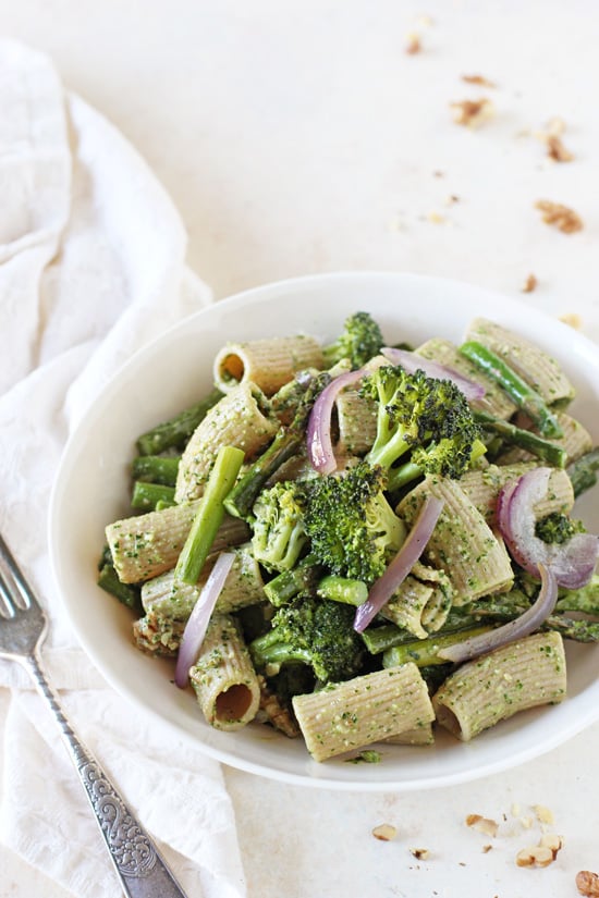 A white bowl filled with Vegan Pesto Pasta with a fork to the side.