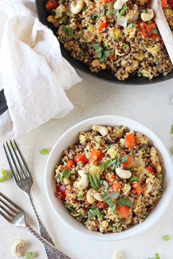 A white bowl filled with Healthy Quinoa Fried Rice with a skillet in the background.