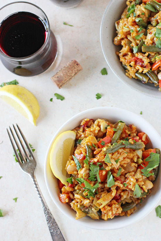 Two bowls filled with Vegan Paella with a wine glass to the side.