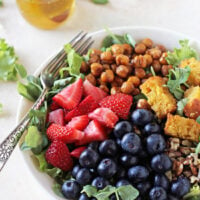 Filled with strawberries, blueberries and spinach, this summer berry chopped salad is perfect for warm weather! Topped with bacon (or chickpea bacon!) and a honey lemon dressing!