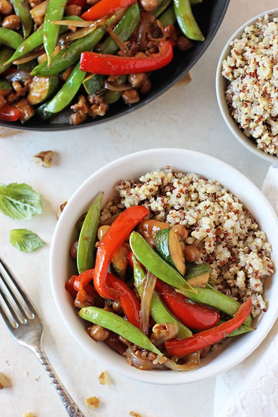 A white bowl filled with Zucchini Stir-Fry and cooked quinoa.