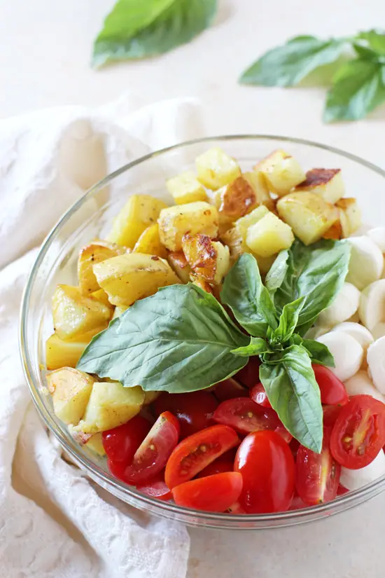 A glass bowl filled with Pesto Potato Salad components.