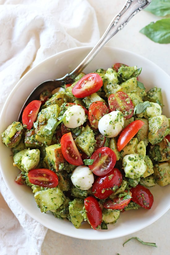 A white bowl filled with Italian Potato Salad with a serving spoon in the dish.