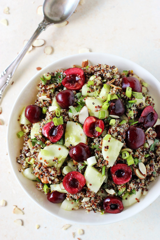 A white bowl filled with Cucumber Quinoa Salad with a serving spoon to the side.
