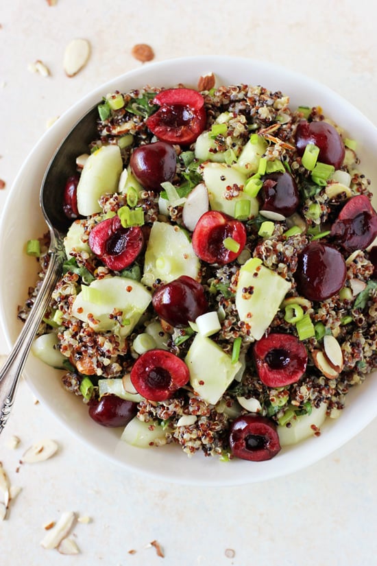A white bowl filled with Cucumber Quinoa Salad with a serving spoon in the dish.