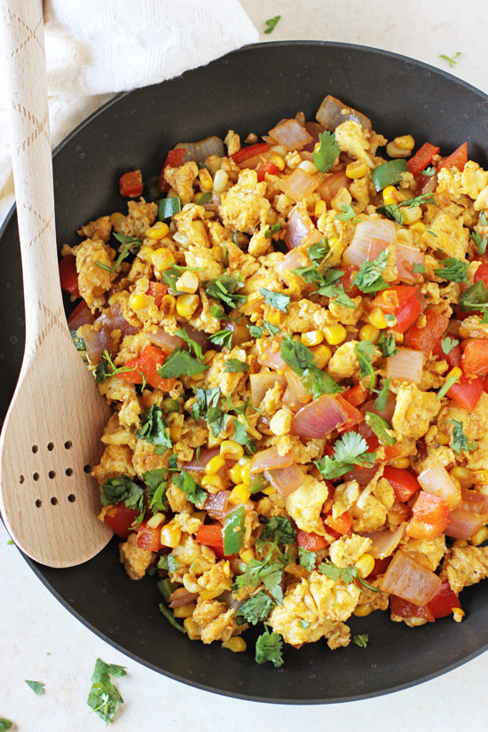 A black skillet filled with Mexican Egg Scramble with a wooden spoon in the pan.
