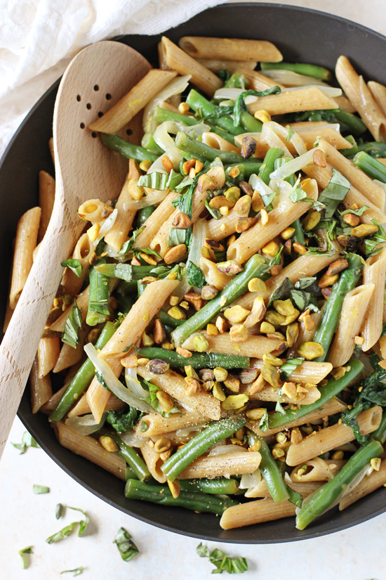 A black skillet filled with Green Bean Pasta with a wooden spoon in the pan.