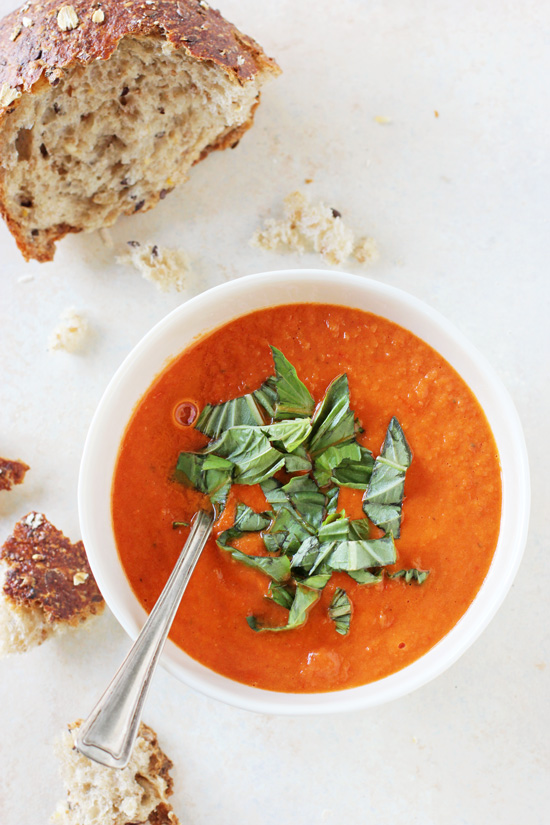 A white bowl filled with Cherry Tomato Soup with a hunk of bread to the side.