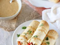 Filled with colorful veggies, cashews and fresh ginger, these baked thai vegetable taquitos are a family favorite! Served with an orange peanut sauce for dipping!