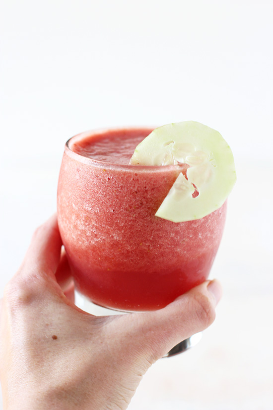 A hand holding up a glass filled with Healthy Watermelon Smoothie.