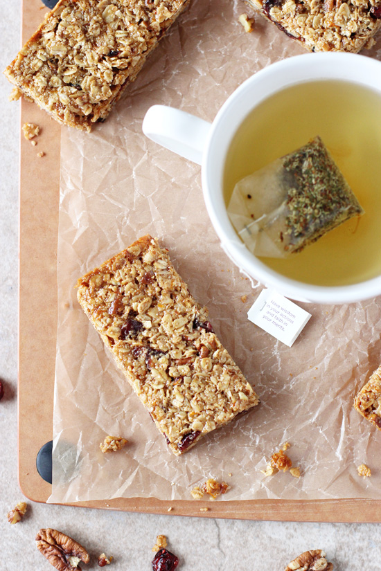 Several sliced Cranberry Granola Bars on a cutting board with a cup of tea.