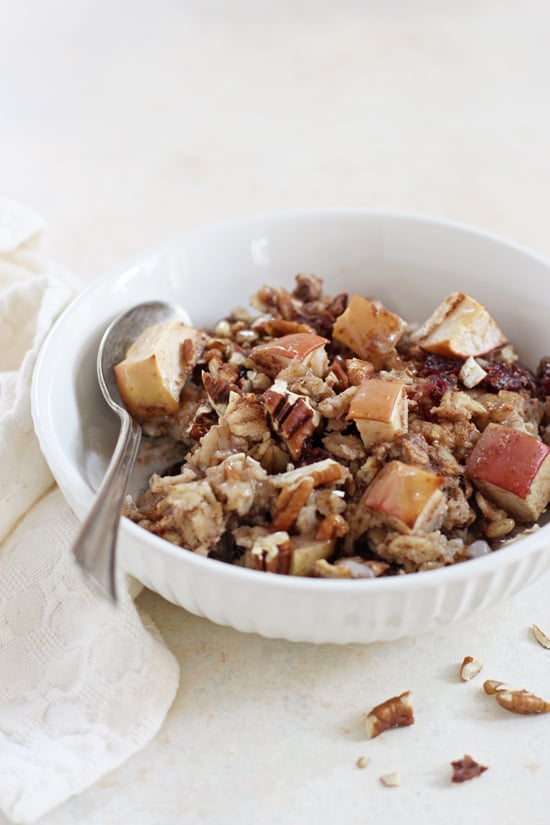 A white bowl filled with Cranberry Apple Baked Oatmeal with a silver spoon in the bowl.