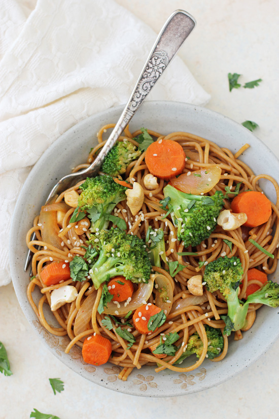 A grey bowl filled with Broccoli Carrot Stir-Fry with a fork in the bowl.