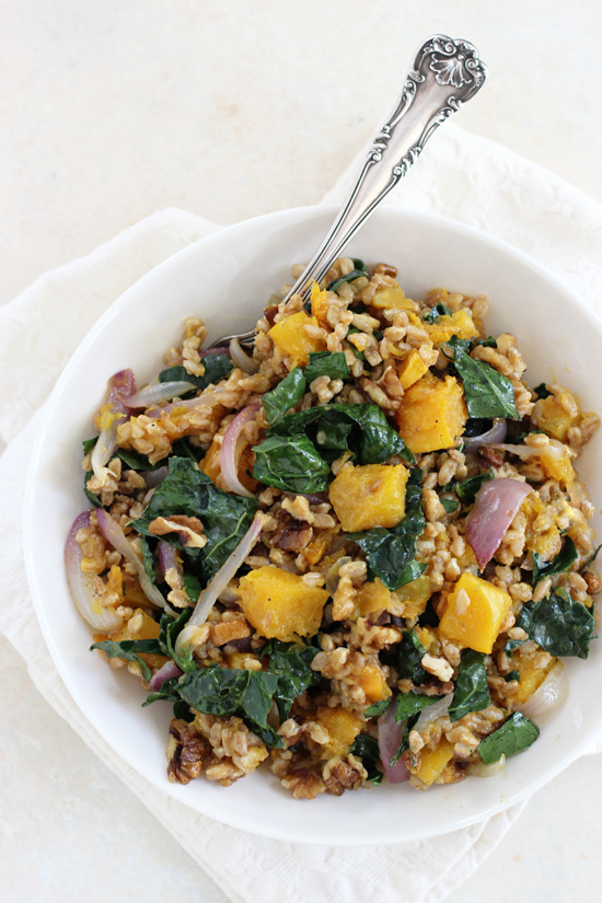A white bowl filled with Butternut Squash Farro with a white napkin and silver spoon.