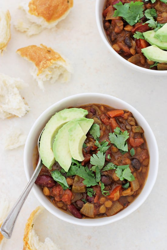 A bowl filled with Vegetarian Pumpkin Chili with torn bread to the side.