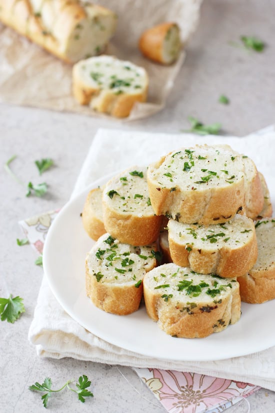 Slices of Homemade Freezer Garlic Bread stacked on a white plate.