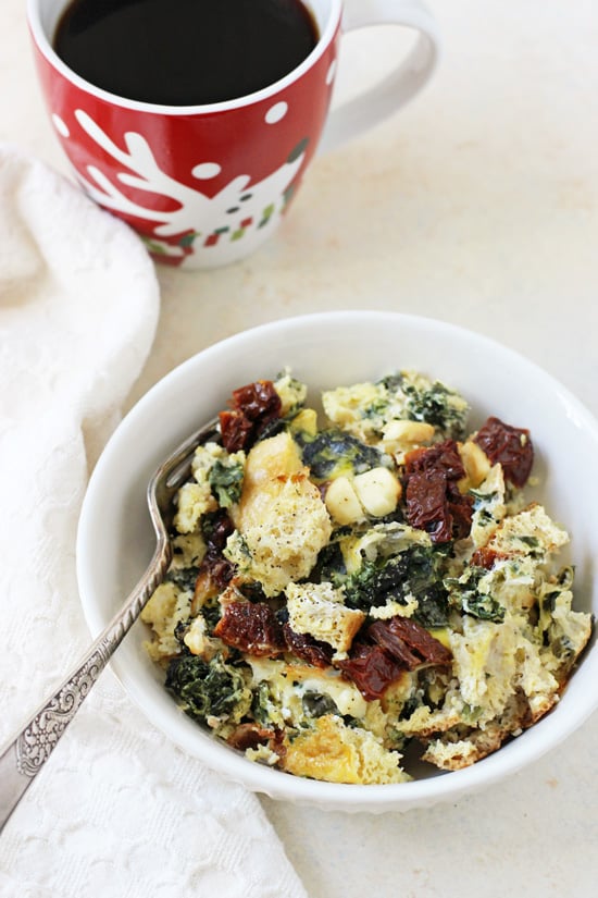 A white bowl filled with Slow Cooker Spinach Feta Egg Casserole with a cup of coffee in the background.