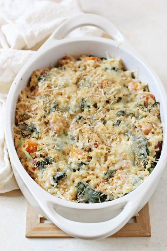 A white baking dish filled with Sweet Potato and Kale Brown Rice Casserole with a white napkin to the side.