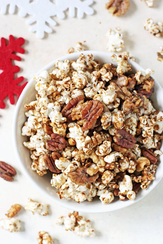 A white bowl filled with Sweet & Spicy Popcorn Nut Party Mix with snowflake coasters in the background.