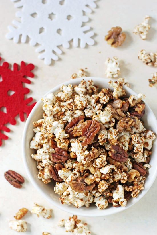 Overhead view of a white bowl filled with Sweet & Spicy Popcorn Nut Party Mix with snowflake coasters to the side.