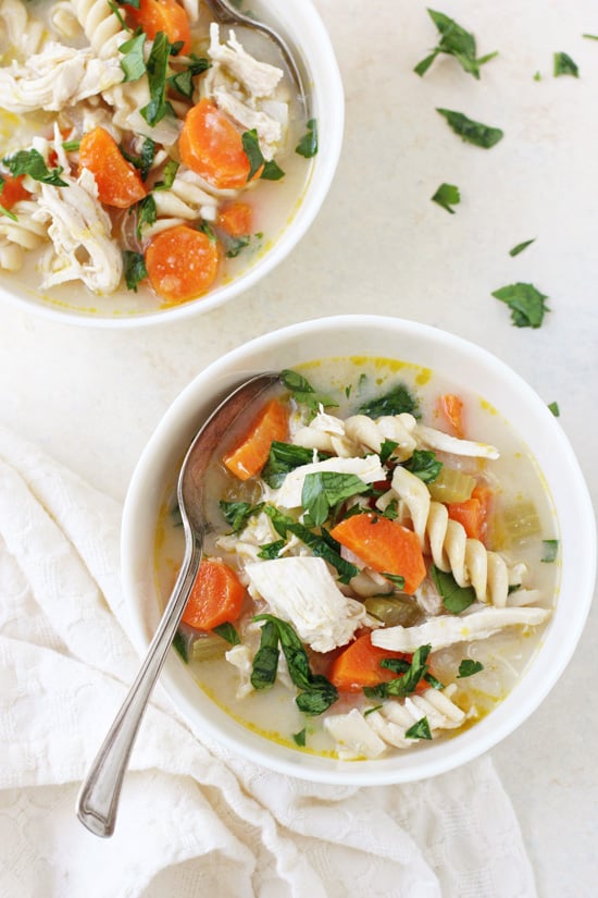 An overhead view of two bowls of Miso Chicken Noodle Soup with spoons in both bowls.