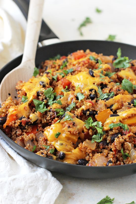 Stuffed Pepper Quinoa Skillet in a black pan with a wooden spoon and a white napkin to the side.