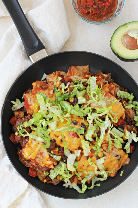 Overhead view of Vegetable & Black Bean Taco Skillet in a black pan with salsa and avocado to the side.