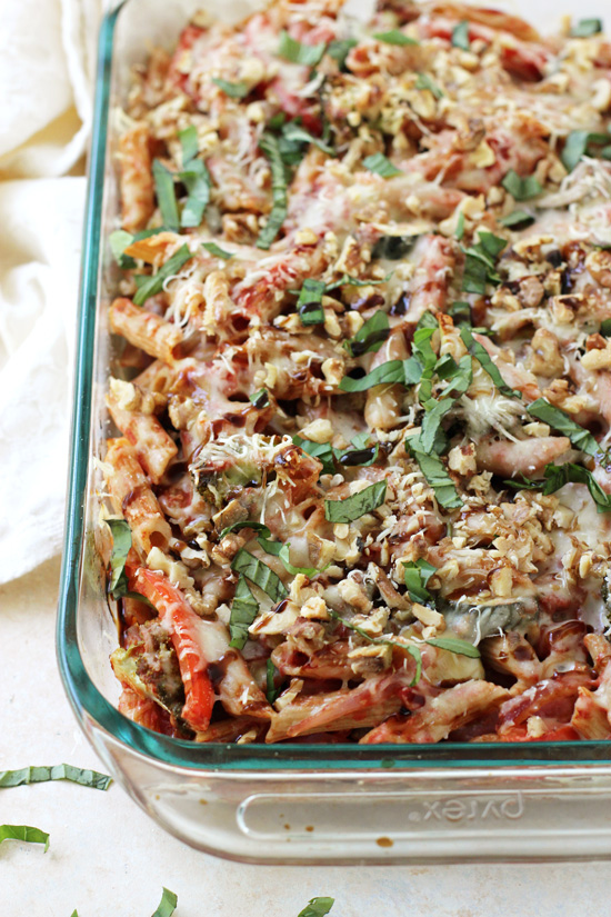 A glass baking dish filled with Roasted Vegetable Baked Ziti and a white napkin to the side.