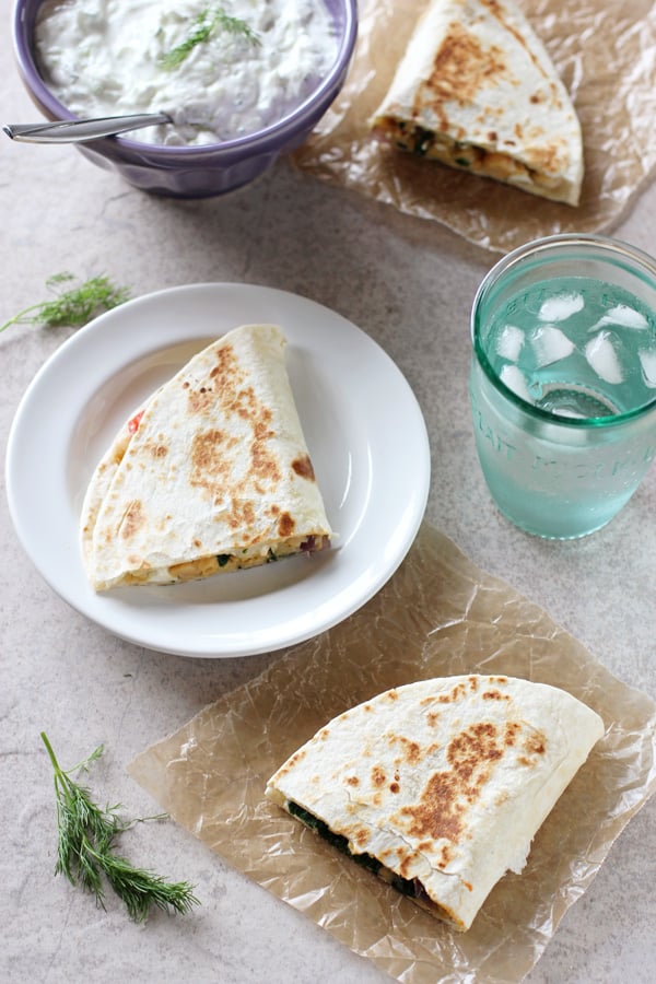 Overhead view of three triangles of Greek Chickpea Quesadillas with tzatziki and a glass of water to the side.