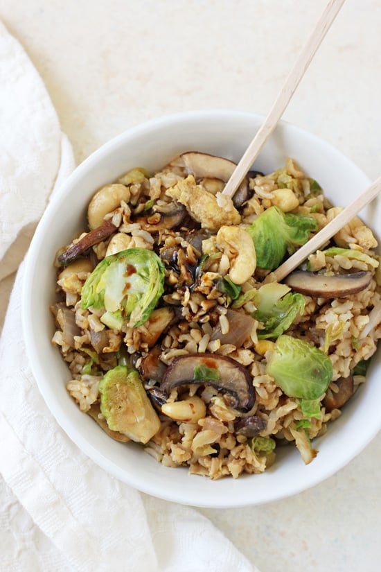 Brussels Sprout Fried Brown Rice in a white bowl with chopsticks and a napkin to the side.