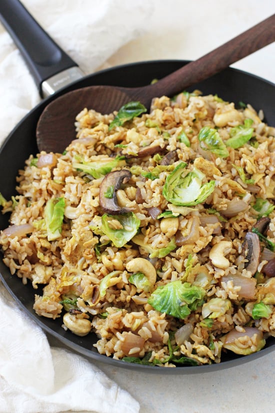 Healthy Fried Brown Rice in a skillet with a wooden spoon.