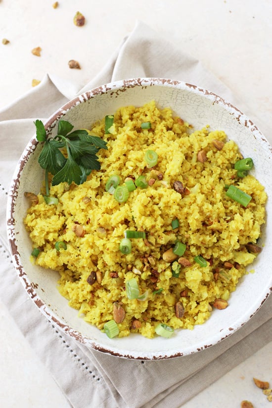 A white bowl filled with Turmeric Cauliflower Rice and a beige napkin underneath.