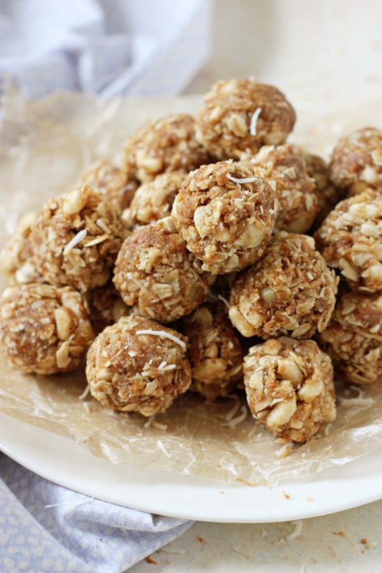 Side angle view of a plate stacked with Coconut Energy Balls with a blue napkin to the side.