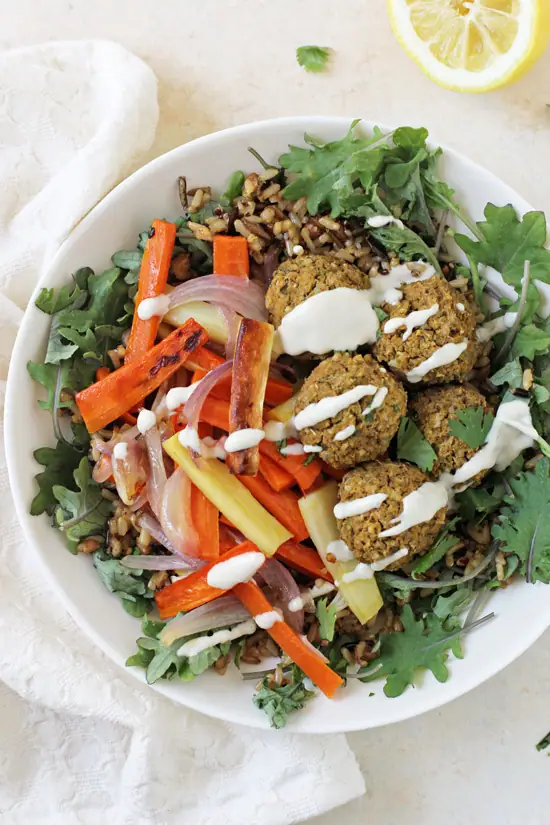 Baked Sweet Potato Falafel in a bowl with roasted veggies and greens.