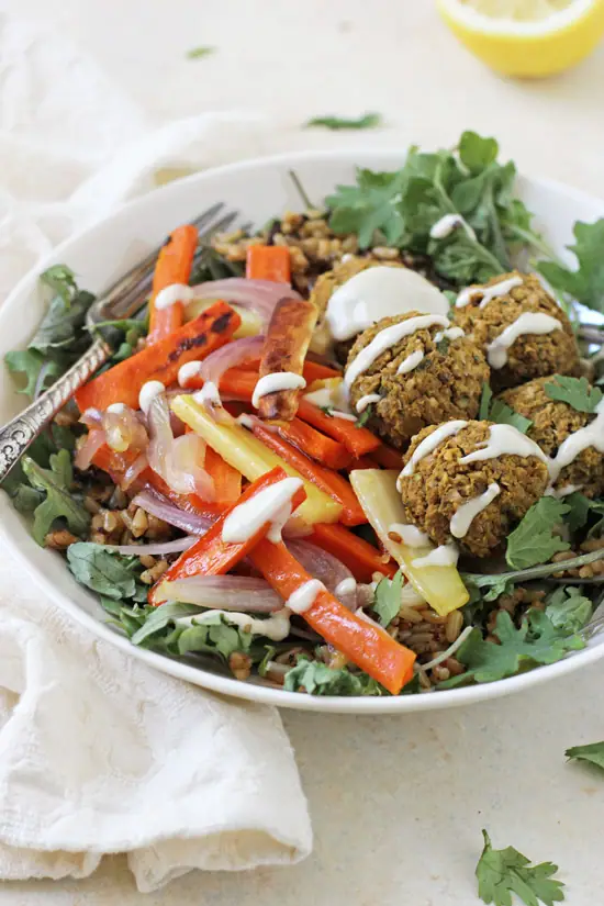 A side angle view of Baked Sweet Potato Falafel in a bowl with a fork and napkin to the side.