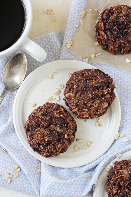 Two Chocolate Cherry Almond Breakfast Cookies on a plate with coffee and more cookies to the side.