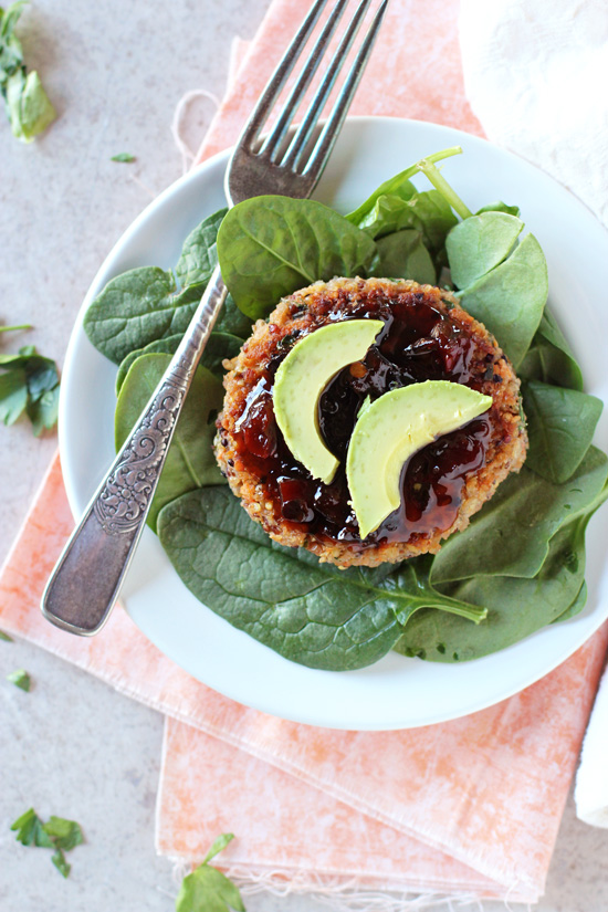 A Quinoa Veggie Burger over greens and topped with avocado and pepper jelly.