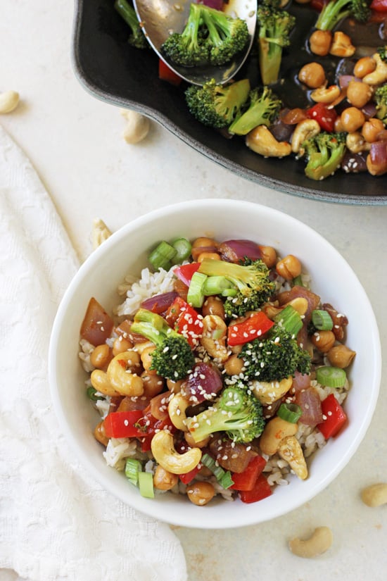 Orange Chickpea and Broccoli Stir-Fry in a bowl with a skillet in the background.
