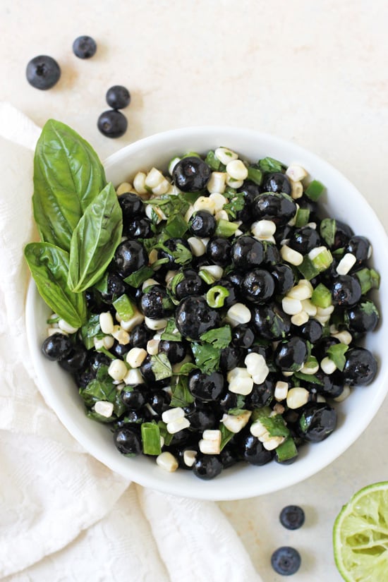 Blueberry Corn Salsa in a white bowl with blueberries and a lime on the side.