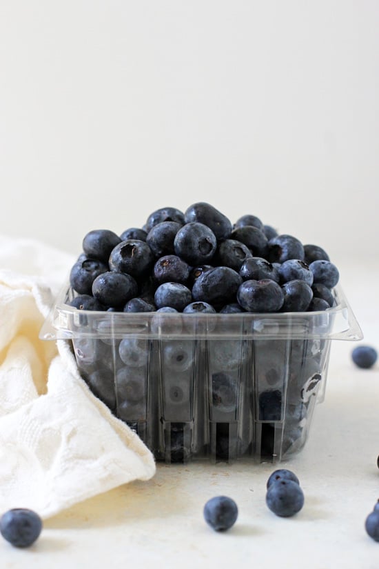 A pint of fresh blueberries with a white napkin to the side.