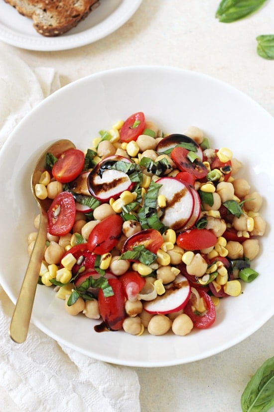 Overhead view of a bowl of Garden Veggie Balsamic Chickpea Salad with a gold spoon.