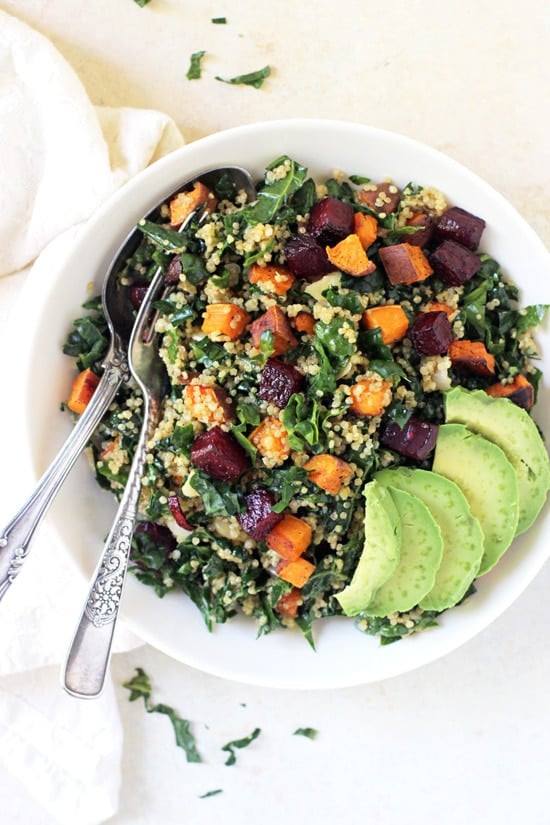 An overhead view of Kale and Quinoa Salad in a bowl with a fork and spoon and a napkin to the side.